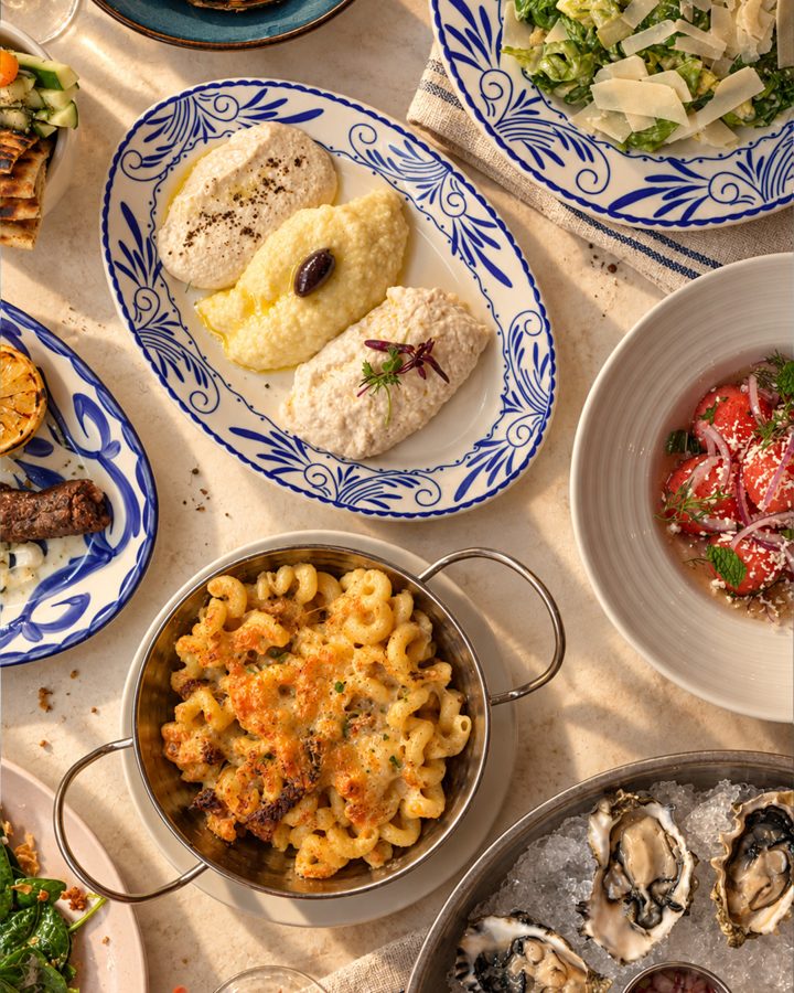 Shared plates across the table: oysters on ice, shrimp, salads and dips